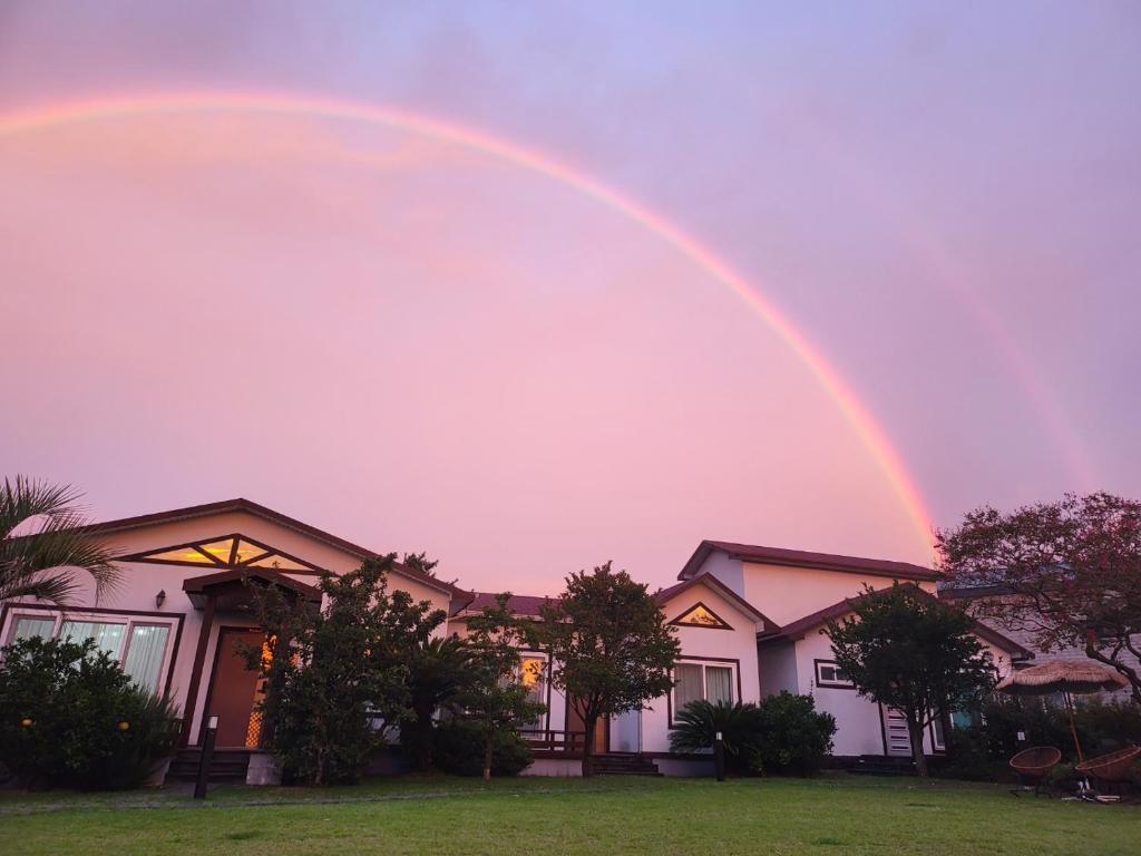 a rainbow in the sky above a house at Gla Aewol in Jeju