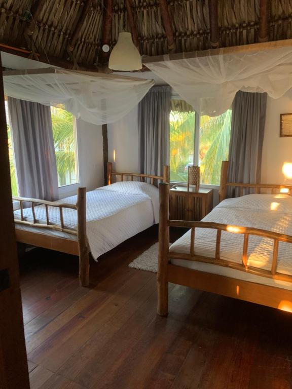 two beds in a room with two windows at Cabo tortugas - casa in Monterrico