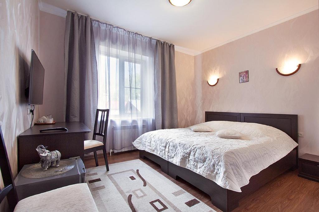 a bedroom with a bed and a desk and a window at Piramida Hotel in Samara