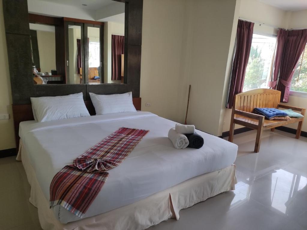 una camera da letto con un grande letto bianco con un orsacchiotto sopra di Baan Thara Guesthouse ad Aonang Beach