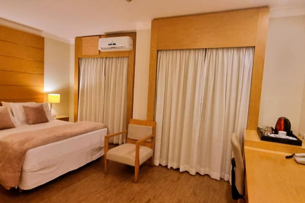 Habitación de hotel con cama y silla en Linda suite em hotel aeroporto de Congonhas, en São Paulo