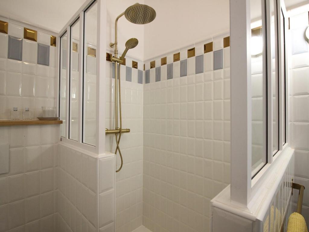 Łazienka z prysznicem wyłożona jest białymi kafelkami. w obiekcie Beau T2 en centre-ville du Mont-Dore, au pied des Thermes, pour 4 pers, bien équipé, ascenseur, Wi-Fi - FR-1-608-241 w mieście Mont-Dore
