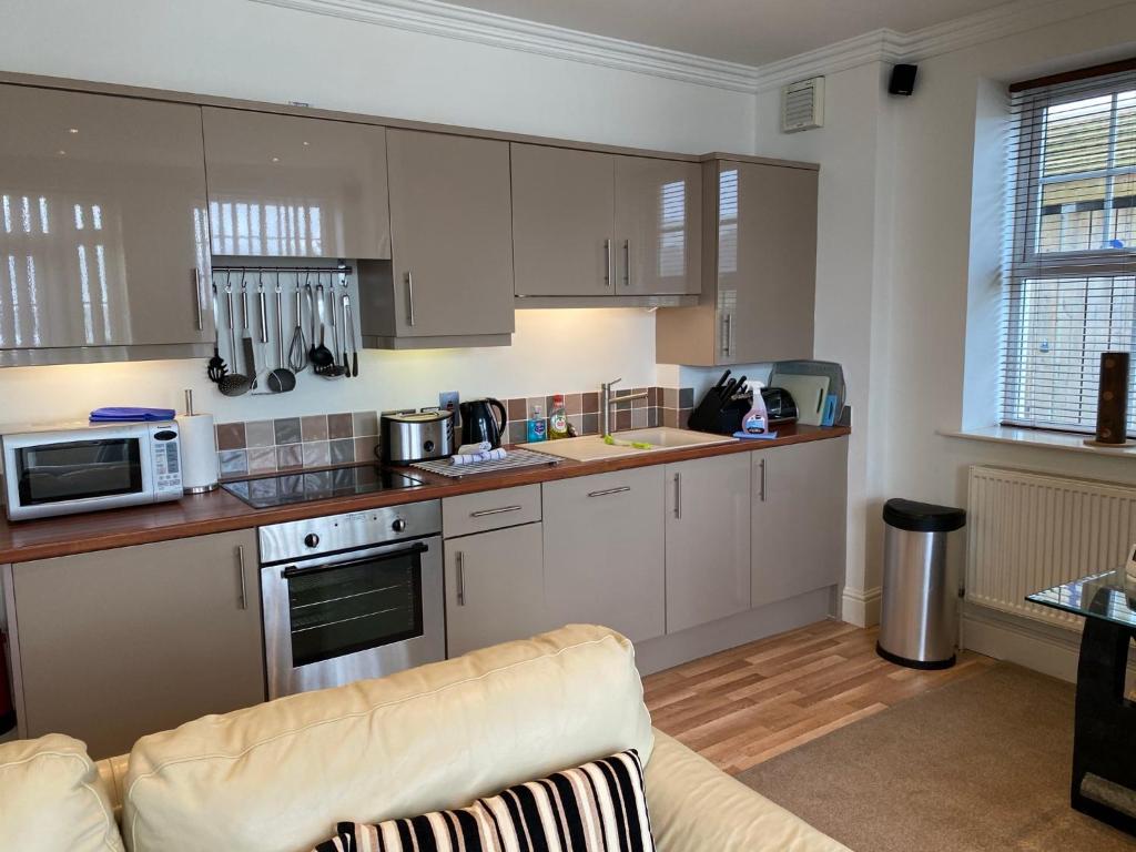 a kitchen with white cabinets and a couch at Southover Beach in Woolacombe