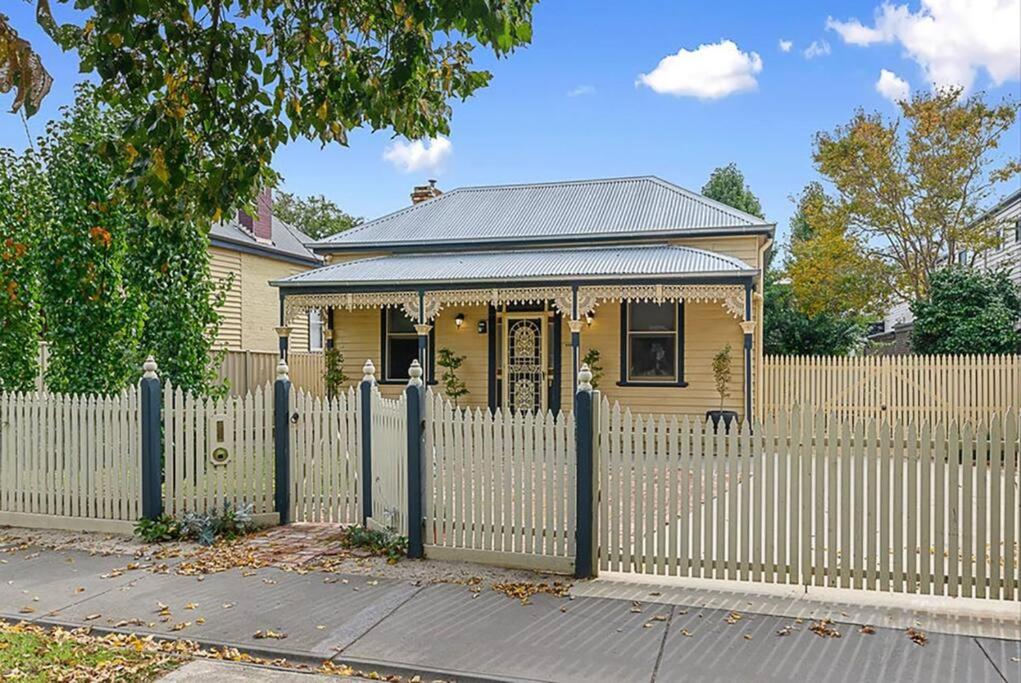 a yellow house with a white picket fence at Heritage Cottage in the heart of Bendigo in Bendigo