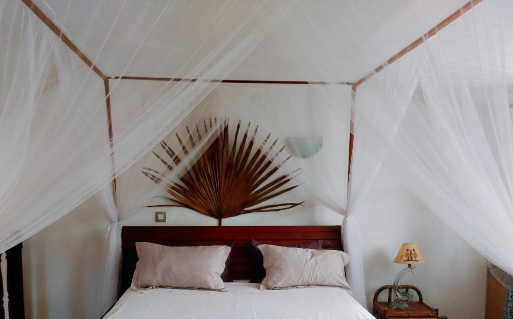 a bedroom with a canopy bed with white curtains at Villa Malandy Appart Hôtel Triplex in Madirokely