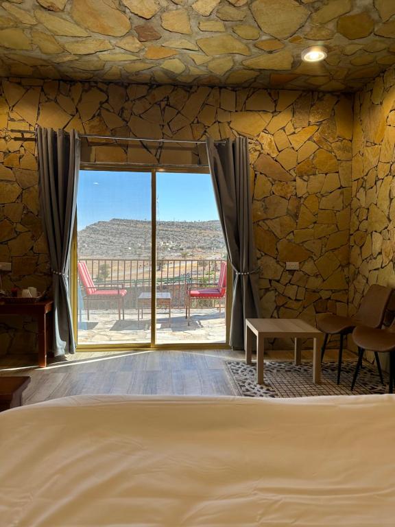 a bedroom with a bed and a large window at jabal shams view stay نزل إطلالة جبل شمس in Al Ḩamrāʼ