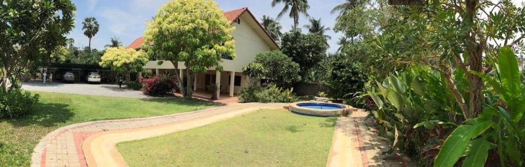 ein Haus mit einem Hof mit einem Teich davor in der Unterkunft Baan Boonsang Pranburi บ้านบุญสร้าง ปราณ in Ban Nong Ban Kao
