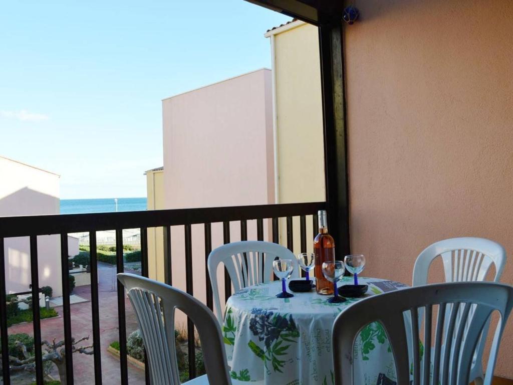einen Tisch mit Stühlen und eine Flasche Wein auf dem Balkon in der Unterkunft Appartement Fleury-Saint-Pierre-la-Mer, 2 pièces, 6 personnes - FR-1-229D-249 in Saint Pierre La Mer