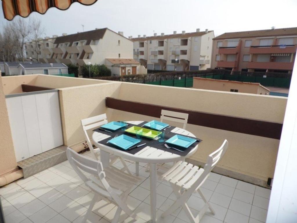 une table blanche et des chaises sur un balcon dans l'établissement Appartement climatisé 2 pièces, accès direct plage, terrasse et parking privé - FR-1-326-531, à Marseillan