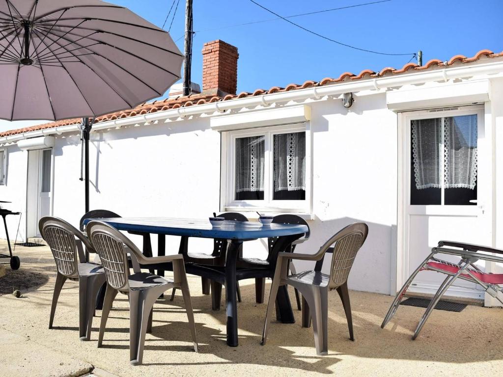 une table, des chaises et un parasol en face d'une maison dans l'établissement Maison de plain pied, 300m de la plage, accès mer privatif, 2 chambres, terrasse et parking - FR-1-224B-33, à Noirmoutier-en-l'lle