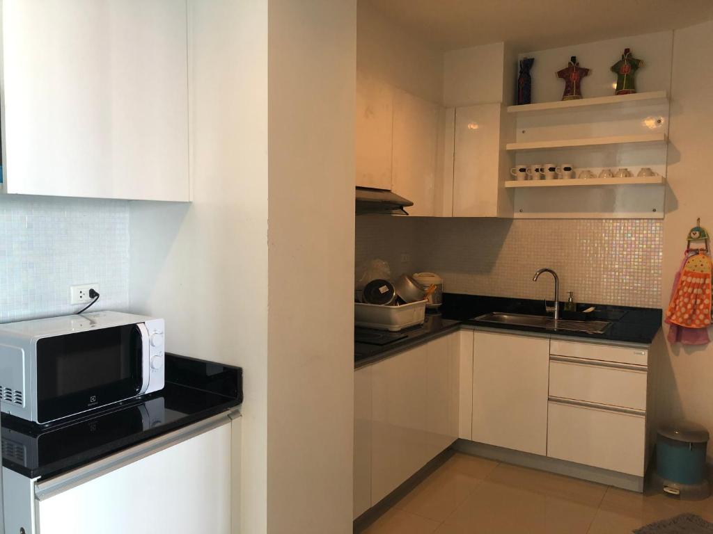a small kitchen with white cabinets and a microwave at Phupha Rayong by gift in Klaeng