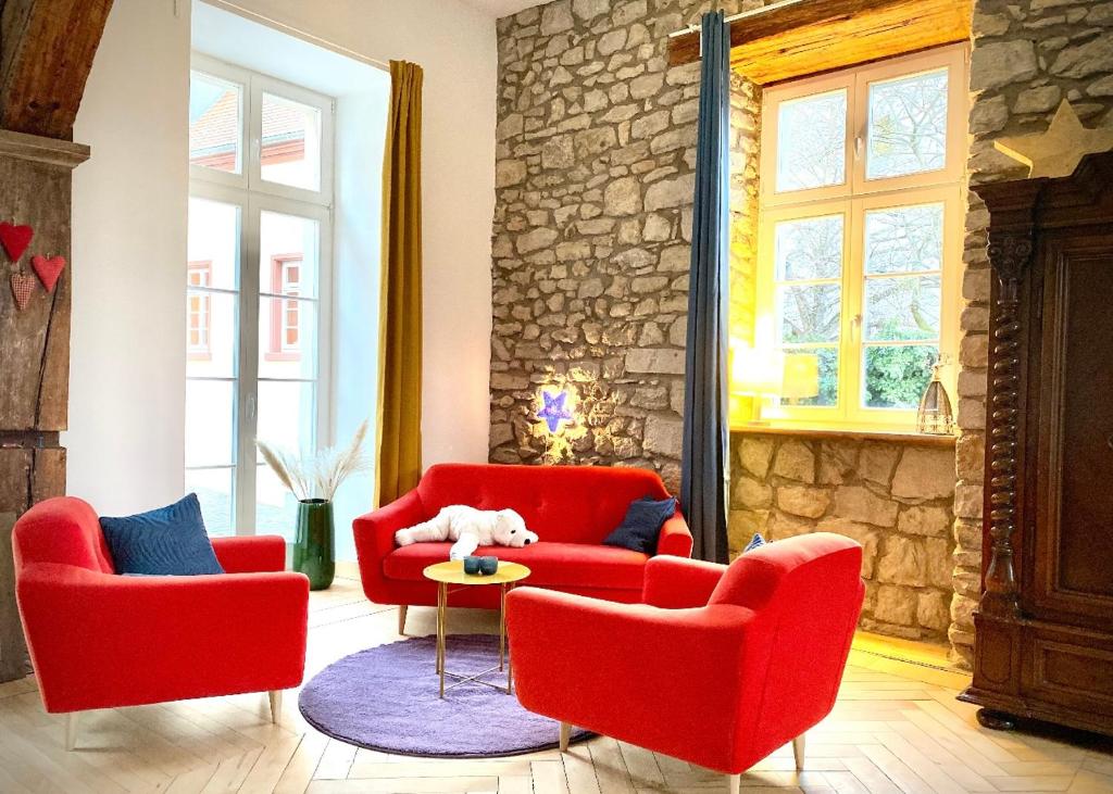 una sala de estar con 2 sillas rojas y una pared de piedra. en Altstadt pur! An der schönen Katharinenkirche en Oppenheim