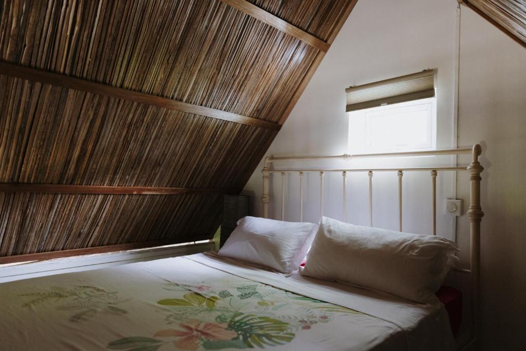 a bed with two pillows in a room with a window at CASE CREOLE INDEPENDANTE PROCHE MER in La Gaulette