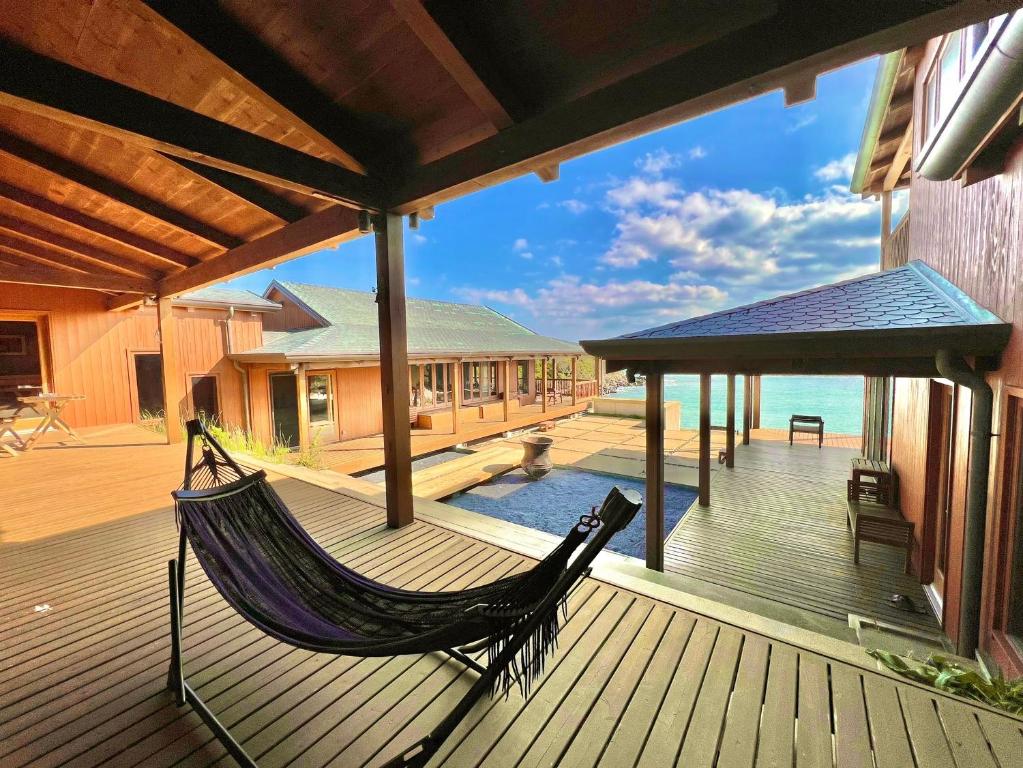 Private beach retreat Resort villa iki by ritomaru في إكي: أرجوحة على سطح المنزل