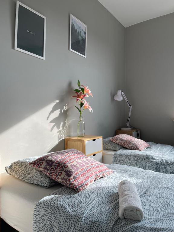 een slaapkamer met 2 bedden en een vaas met bloemen erop bij Szumi Las Bed & Breakfast in Józefów