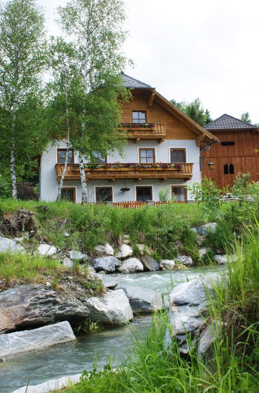 a house on a hill next to a river at Biobauernhof Tonimörtl in Mariapfarr