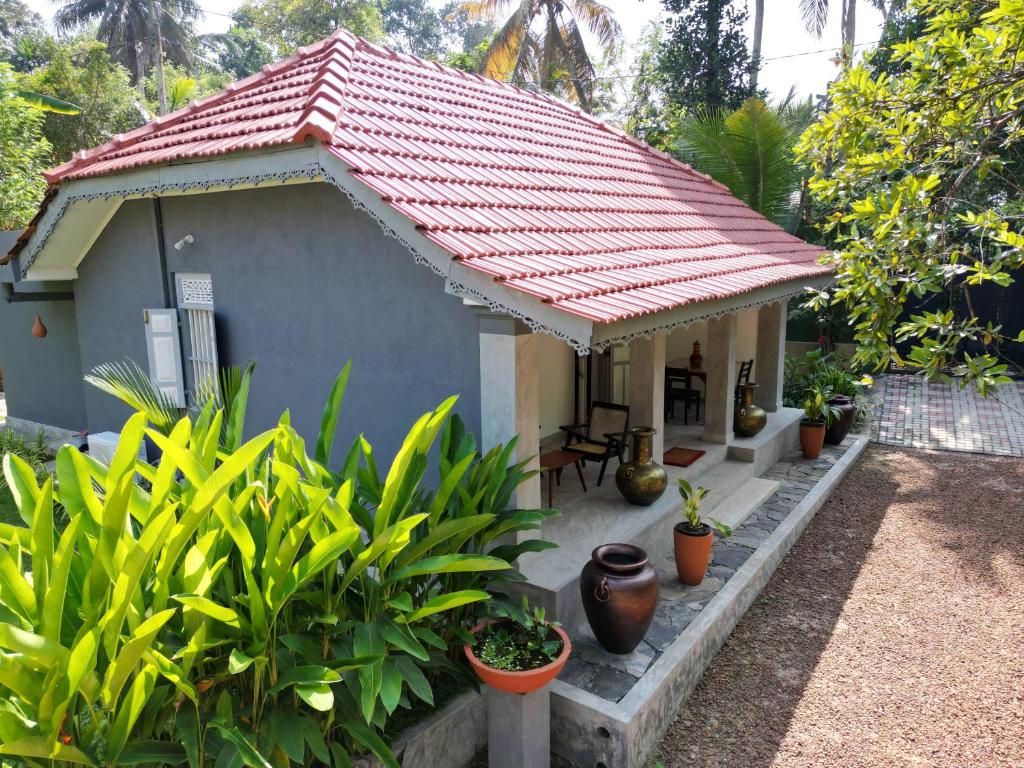a small house with a red roof and plants at Birdsong Villa Private Garden Retreat in Ratgama Hegoda