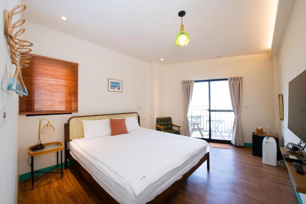 a bedroom with a white bed and a large window at Lixia Hostel in Xiaoliuqiu