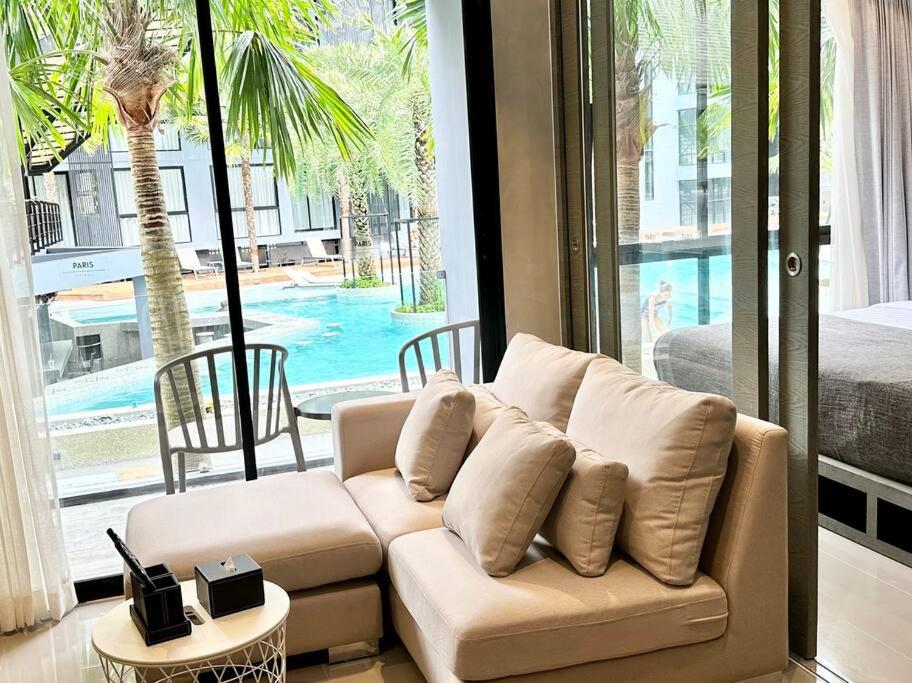 a living room with a couch and a view of a pool at Kamala Beach Pool view Resort P15 in Kamala Beach