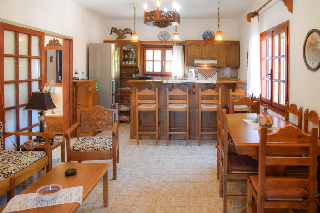 a kitchen with wooden tables and chairs and a kitchen with a refrigerator at Apartment in a summer house close to the sea in Chorefto