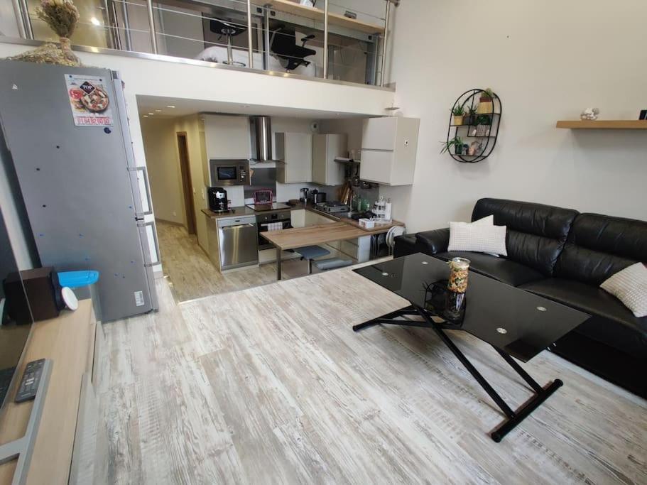 a living room with a black leather couch and a table at Les Capucins in Coulommiers