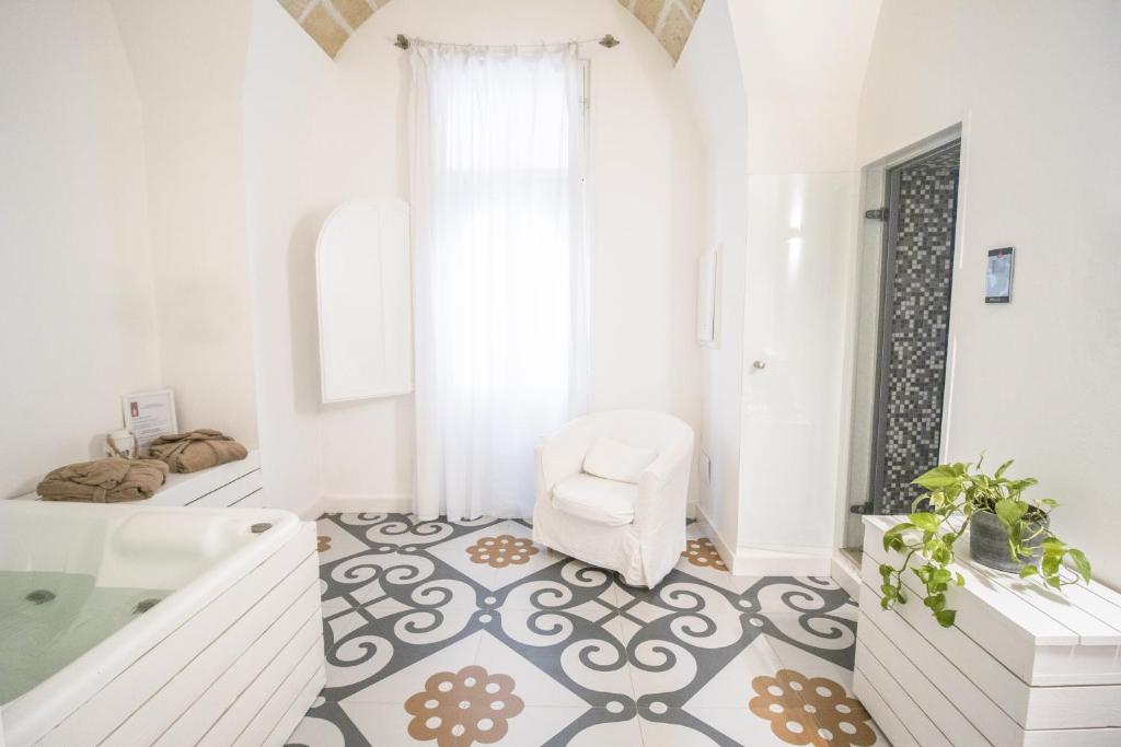 Sui Tetti Luxury Rooms في ليتشي: حمام مع حوض استحمام وكرسي