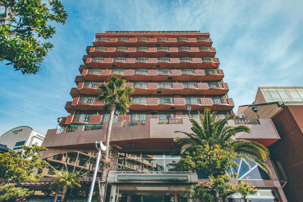 a tall building with palm trees in front of it at Hotel Villa Kuretake in Hamamatsu