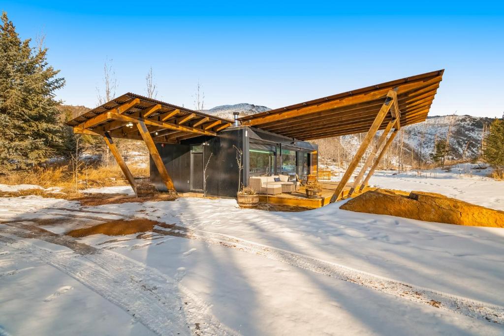 une maison en verre dans la neige dans les bois dans l'établissement Tree Farm Sanctuary, à Basalt