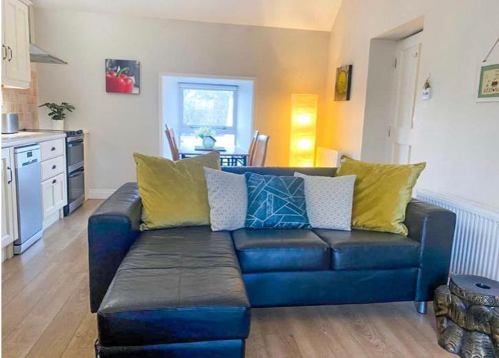 uma sala de estar com um sofá azul com almofadas amarelas em Village Way Apartments em Kincasslagh