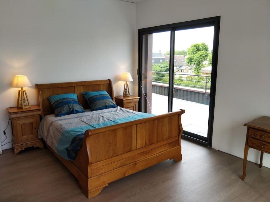 Schlafzimmer mit Holzbett und Balkon in der Unterkunft Appartement au Crotoy in Le Crotoy