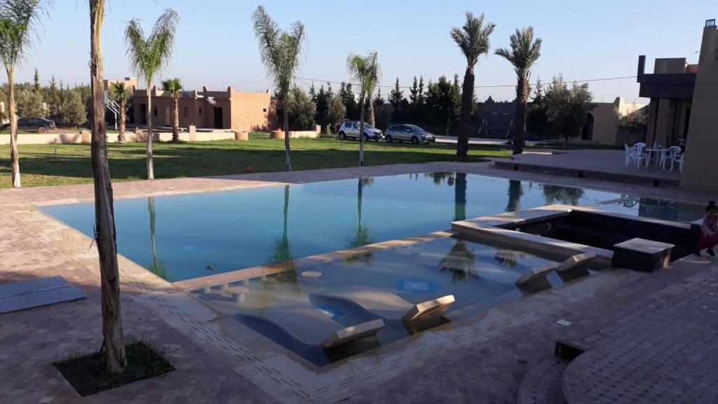 a swimming pool with chairs and a palm tree at Tanazart guest house in Taroudant