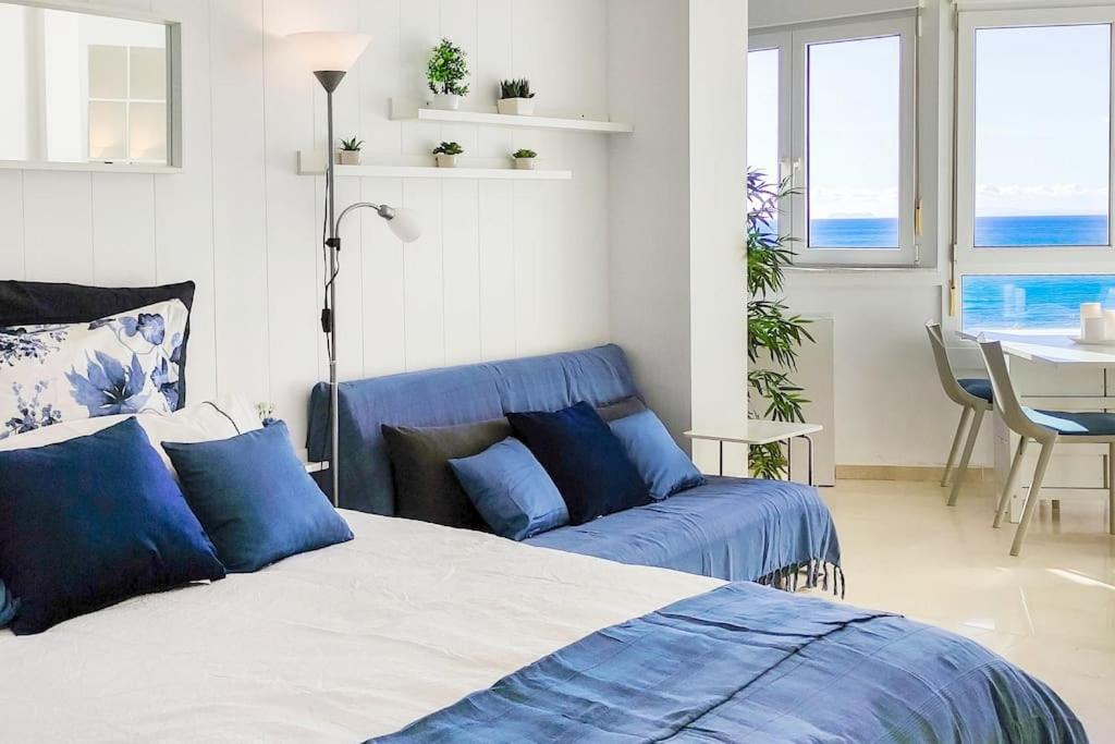 a bedroom with a bed and a blue couch at ALGAIDA BEACHFRONT - Seaview Costa del sol in Sitio de Calahonda