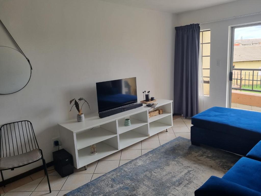 a living room with a tv on a white cabinet at The cozy 1 bedroom apartment in Midrand