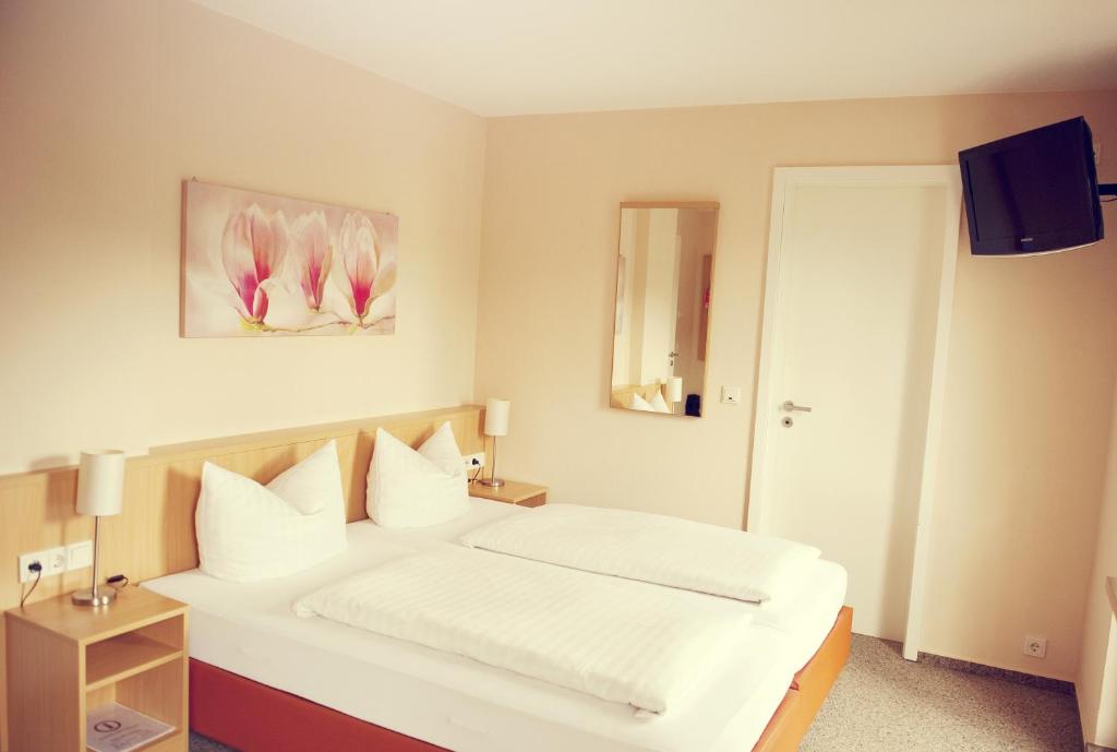 een slaapkamer met een wit bed met witte kussens bij Tafelspitz in Limburg an der Lahn