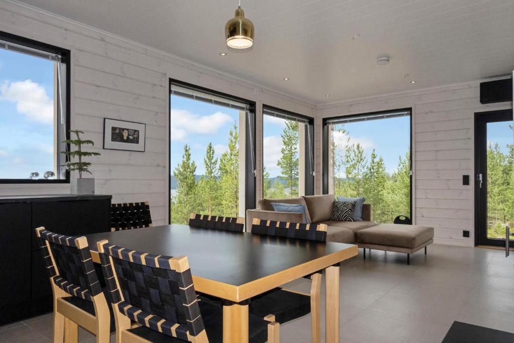 a living room with a table and a couch and windows at Villa Horihane - Modern Villa with panoramic view in Ivalo