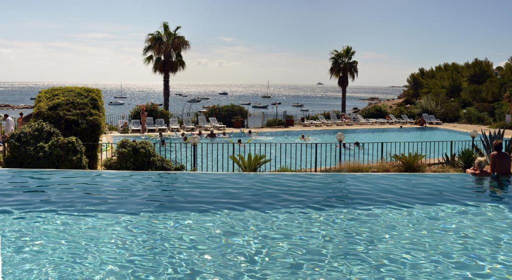 a swimming pool with the ocean in the background at Village Naturiste La Chiappa in Porto-Vecchio