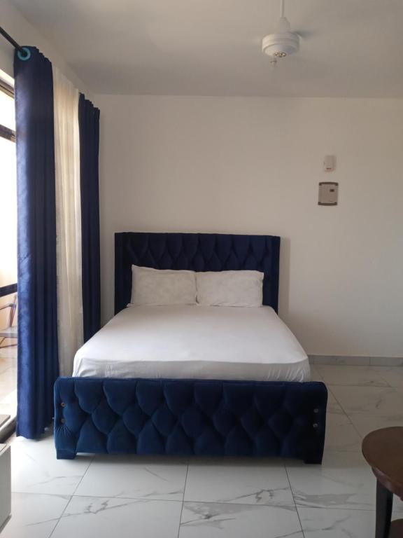 a bed with a blue tufted bed frame in a room at Amber Apartment in Mombasa