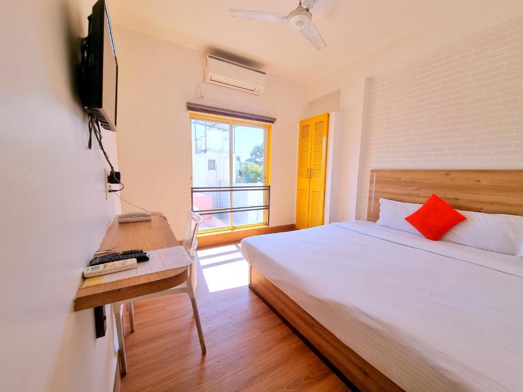 a bedroom with a bed and a television and a window at Stayinn Nest in Bhopal