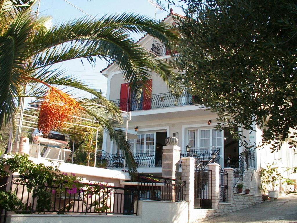 a white house with palm trees in front of it at Epicharis Studios in Vathi