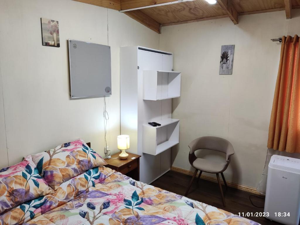 1 dormitorio con cama, silla y espejo en Hospedaje Lago Llanquihue, en Llanquihue