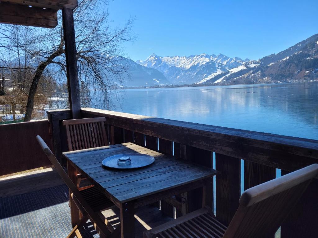 a wooden table and chairs on a balcony overlooking a lake at Waterfront Apartments Zell am See - Steinbock Lodges in Zell am See