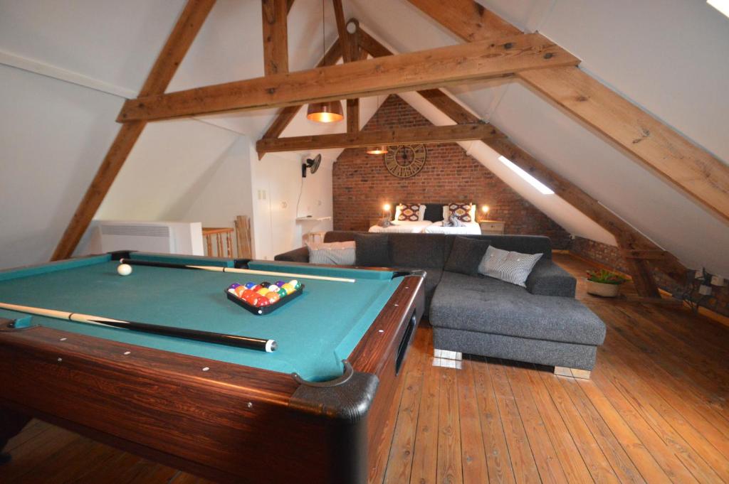 uma sala de estar com uma mesa de bilhar e um sofá em Birdsonghouse em Ypres