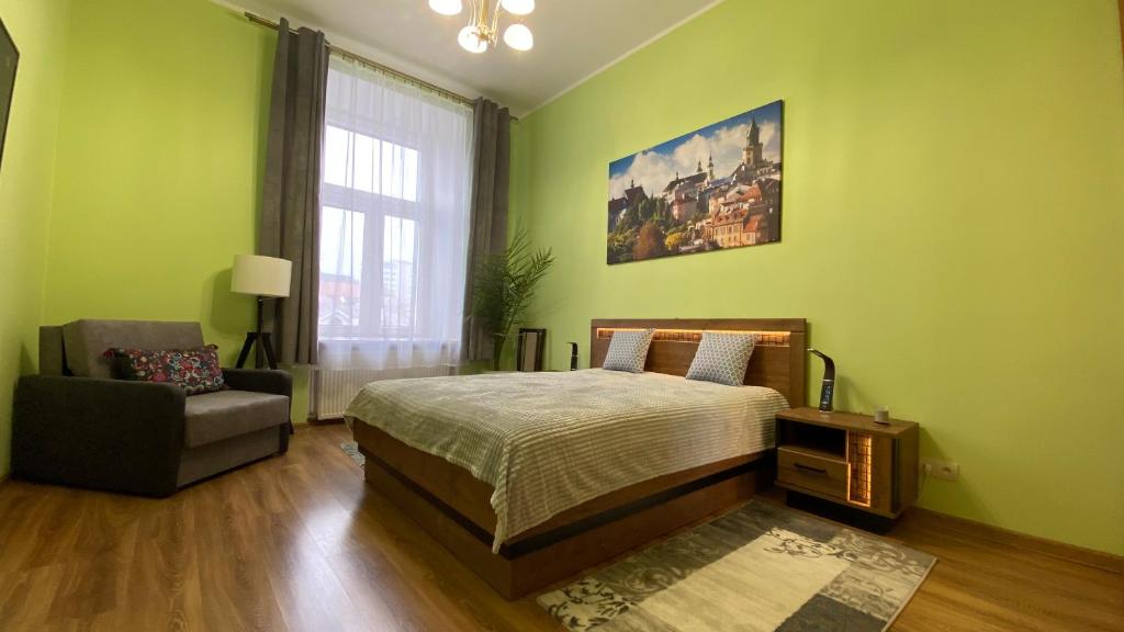 ein Schlafzimmer mit grünen Wänden, einem Bett und einem Stuhl in der Unterkunft LublinBNB --- Zolnierzy Niepodleglej 7 --- CENTRUM , PLAC LITEWSKI --- SWIEZO PO REMONCIE in Lublin