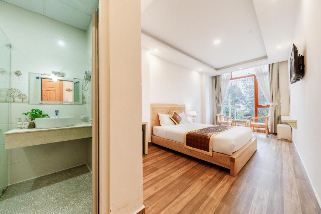 - une chambre avec un lit, un lavabo et un miroir dans l'établissement Golden Bee Hotel, à Đà Lạt