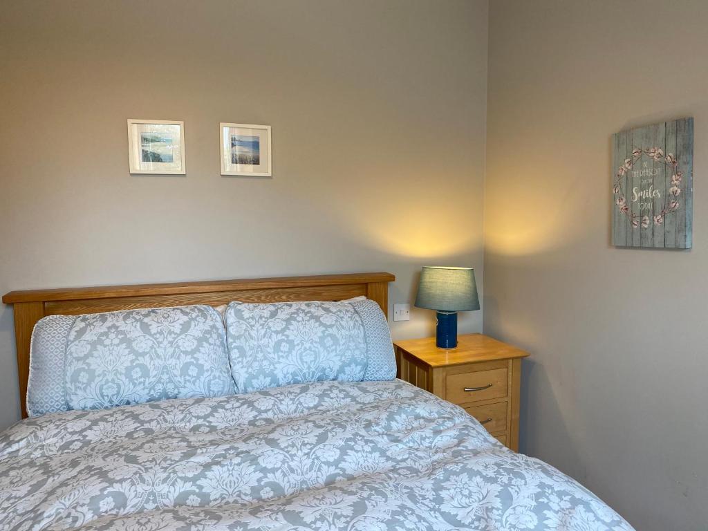 a bedroom with a bed and a lamp on a night stand at Village Way Apartments in Kincasslagh