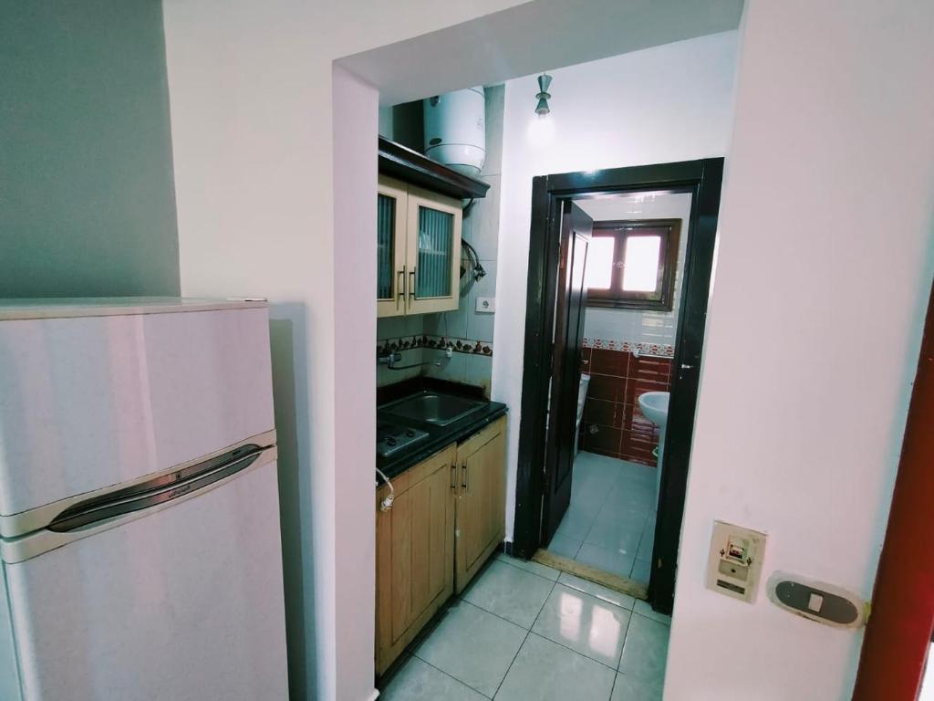 La cuisine est équipée d'un réfrigérateur blanc et d'un évier. dans l'établissement قريه دلتا شرم 106-12, à Charm el-Cheikh