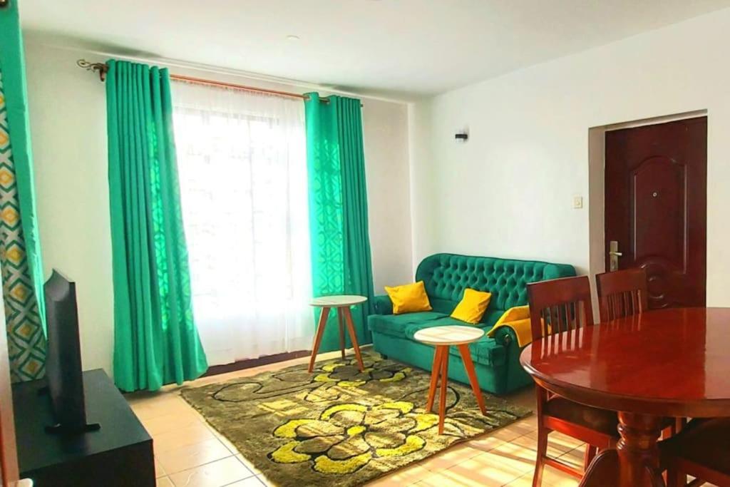 sala de estar con sofá verde y mesa en 2 bedroom Apt 20 min to JKIA Airport,SGR Train St. en Athi River