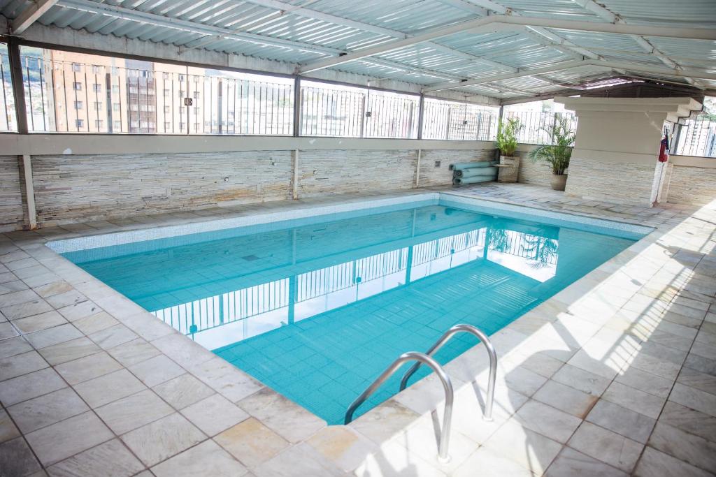 a large swimming pool with blue water in a building at Lisboa Hotel in Poços de Caldas