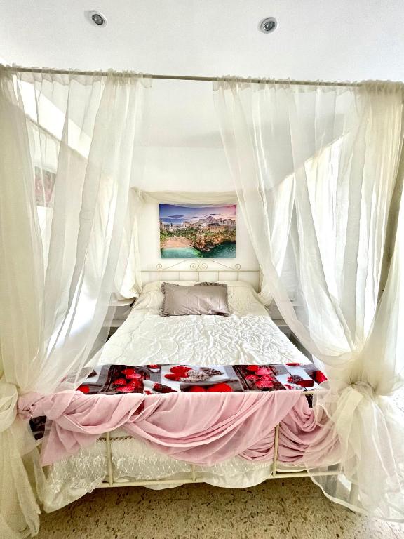 ポリニャーノ・ア・マーレにあるAffittacamere Lulucのベッドルーム(白いカーテン付きの天蓋付きベッド1台付)