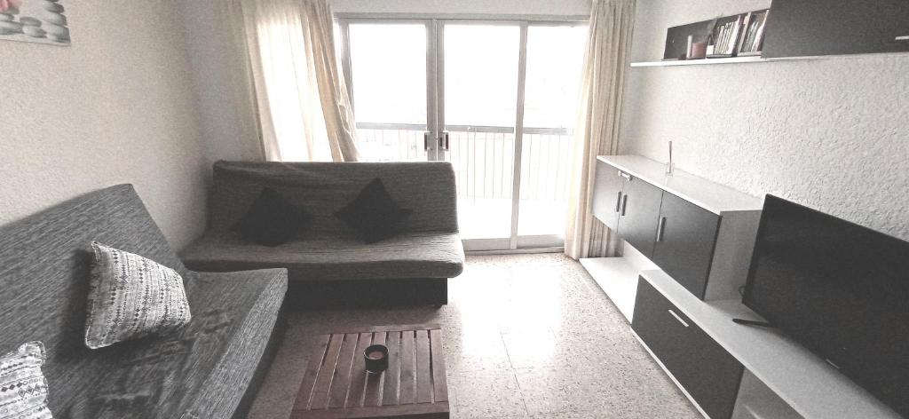 uma sala de estar com um sofá e uma janela em Apartamento Rincon de Loix, soleado, zona jardines y piscina, y zona exterior para aparcar y a la playa a 300,00 mts. em Benidorm